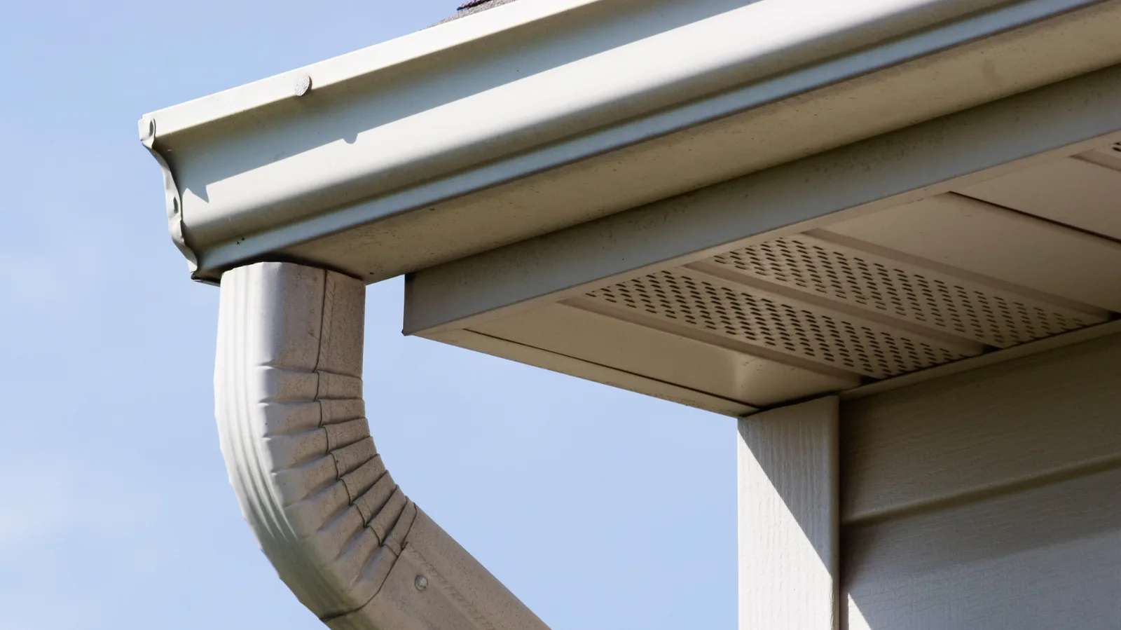 Gutter and downspout beside perforated soffit panels
